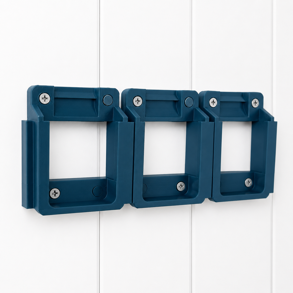 Three Makita blue plastic 18v battery brackets with screws on a white wooden background