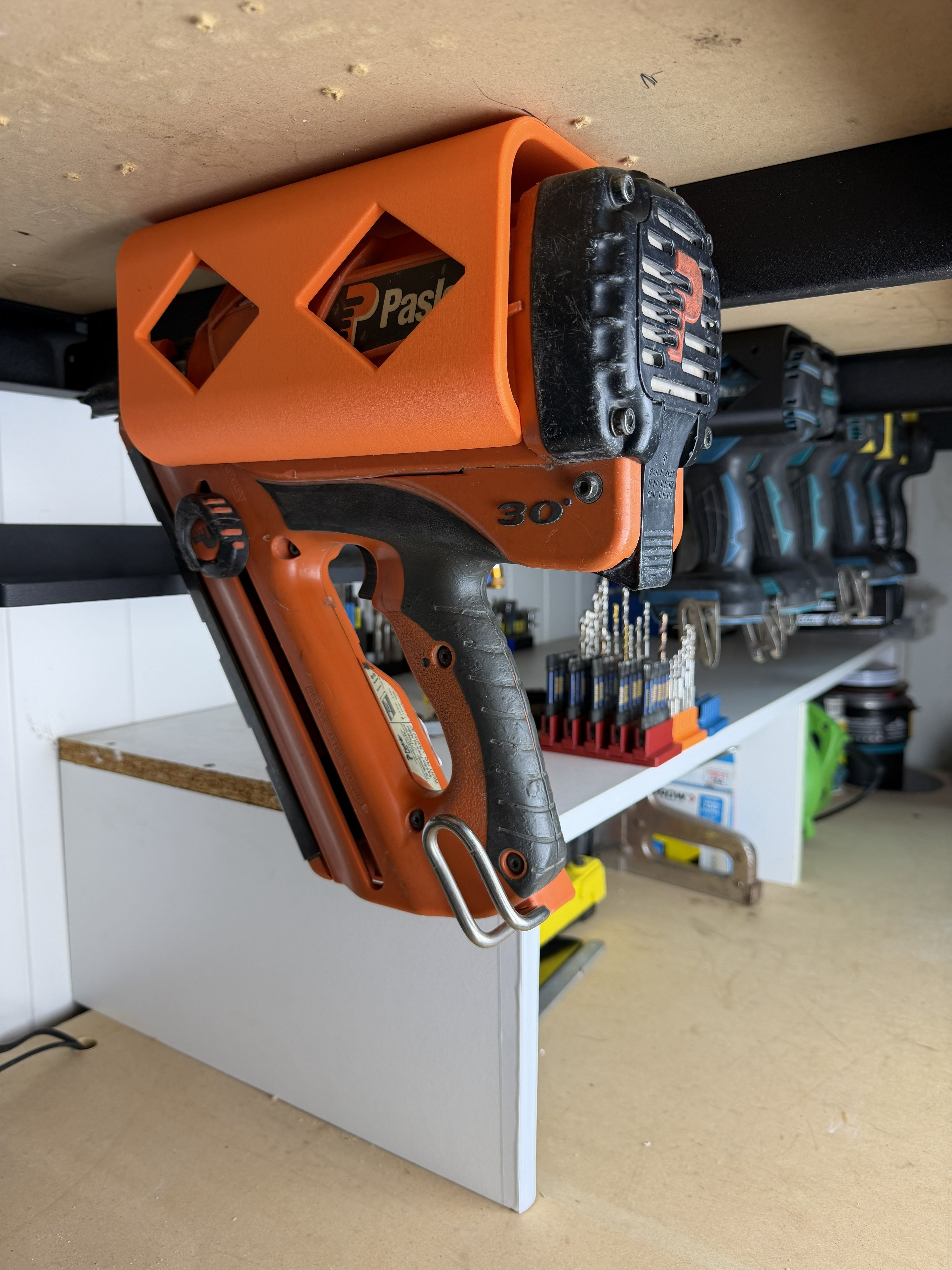 Pneumatic paslode nail gun stored in a tool holster in a workshop setting