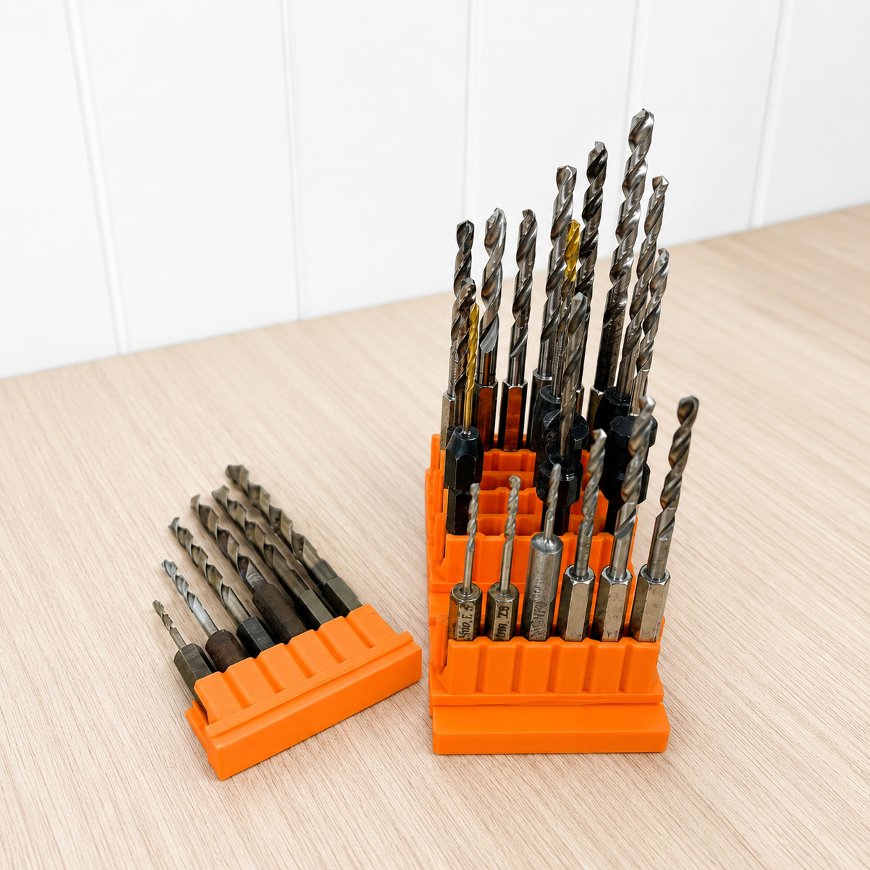 Set of drill bits in an orange holder on a wooden surface